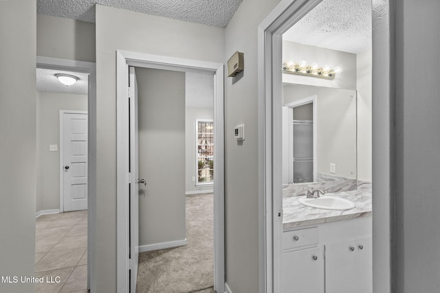 bathroom with baseboards, a textured ceiling, and vanity