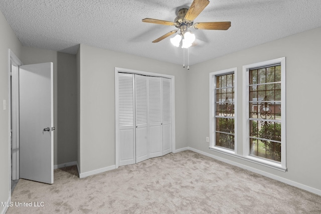 unfurnished bedroom featuring a textured ceiling, a ceiling fan, baseboards, a closet, and carpet