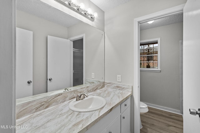 bathroom featuring a textured ceiling, vanity, wood finished floors, and toilet