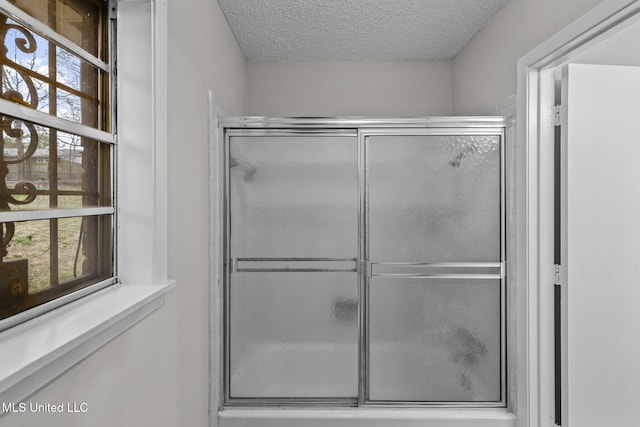 full bath with a shower with shower door and a textured ceiling