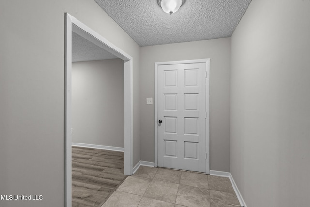 foyer with a textured ceiling, baseboards, and light tile patterned floors