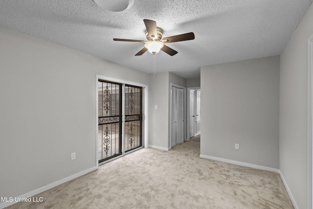 carpeted spare room with ceiling fan, a textured ceiling, and baseboards