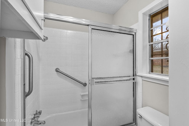 full bath with shower / bath combination with glass door, a textured ceiling, and toilet