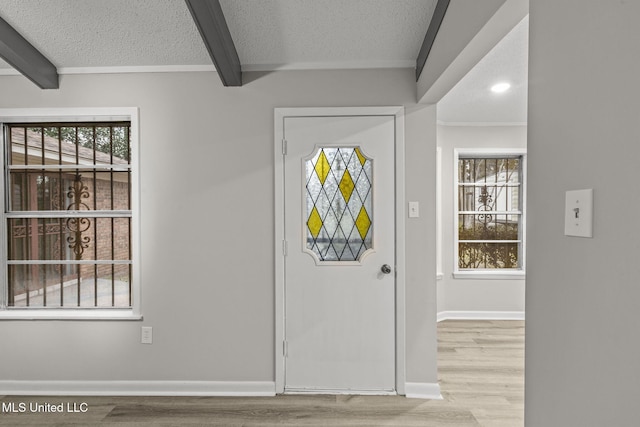 entryway with a textured ceiling, wood finished floors, beam ceiling, and baseboards