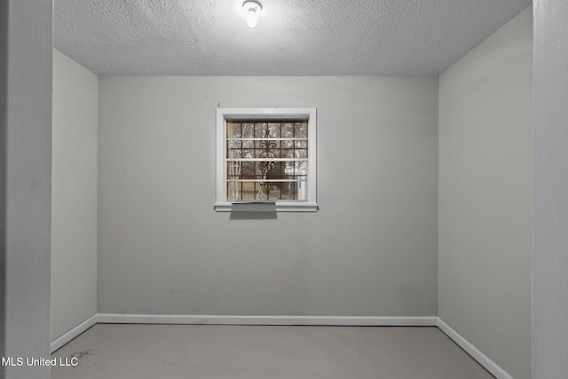 empty room featuring finished concrete flooring, baseboards, and a textured ceiling