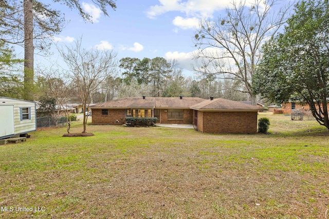 back of house featuring an outbuilding, a yard, brick siding, and fence