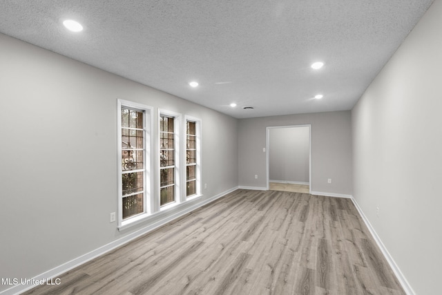 unfurnished room with recessed lighting, a textured ceiling, baseboards, and wood finished floors