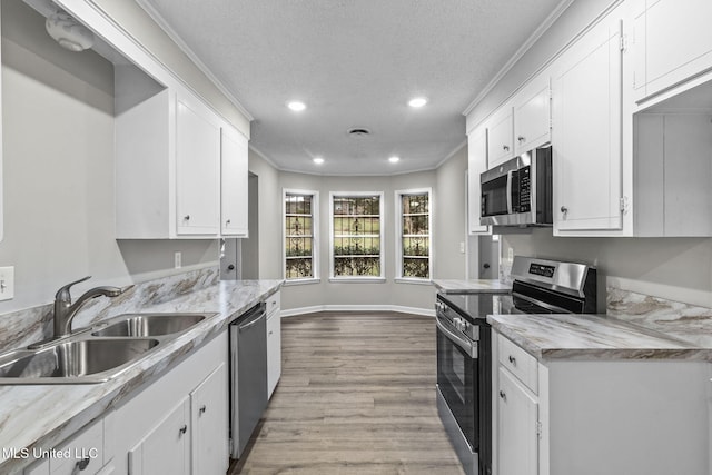 kitchen featuring white cabinetry, crown molding, appliances with stainless steel finishes, and a sink