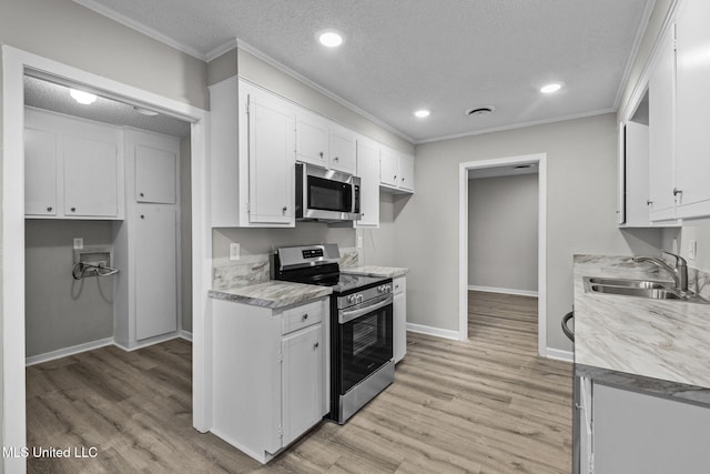 kitchen with crown molding, light wood finished floors, stainless steel appliances, a sink, and a textured ceiling