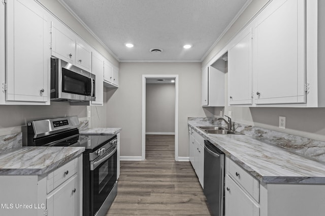 kitchen featuring crown molding, appliances with stainless steel finishes, white cabinets, and wood finished floors