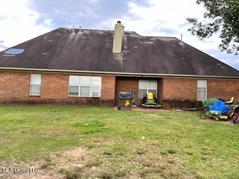 9091 Hunters Ridge Dr, Olive Branch, MS 38654 - rear view of house with a chimney, brick siding, a yard, and a patio area