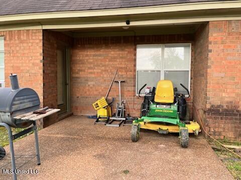 9091 Hunters Ridge Dr, Olive Branch, MS 38654 - view of exterior entry with brick siding, roof with shingles, and a patio