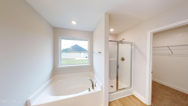 bathroom with hardwood / wood-style flooring and shower with separate bathtub