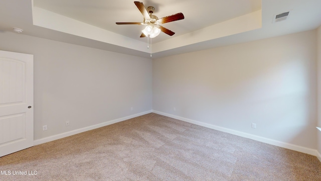 carpeted empty room featuring a tray ceiling and ceiling fan