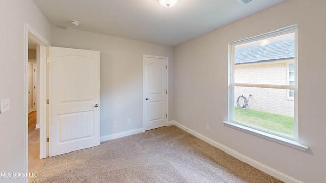 unfurnished bedroom with light colored carpet and multiple windows