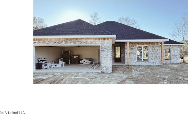 view of front of property featuring brick siding, roof with shingles, and an attached garage