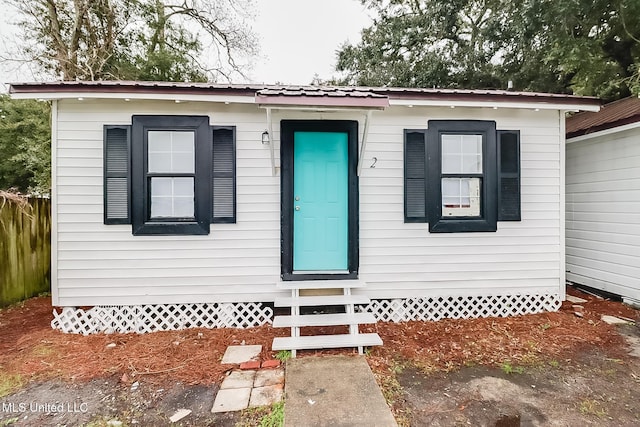 bungalow with entry steps, metal roof, and crawl space