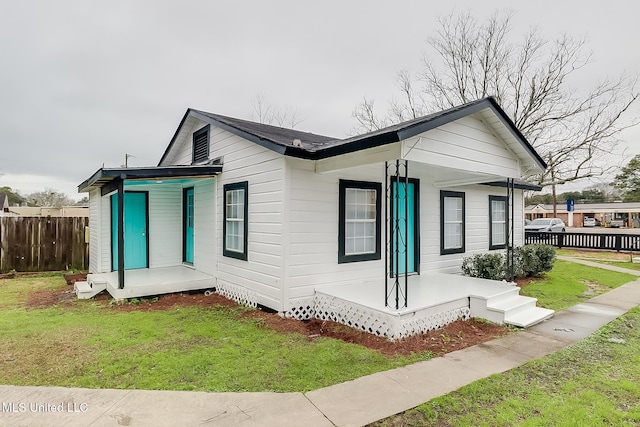 view of front of house with covered porch, fence, and a front yard