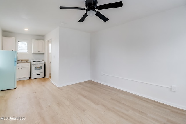 kitchen with white appliances, baseboards, white cabinets, light wood-type flooring, and a sink