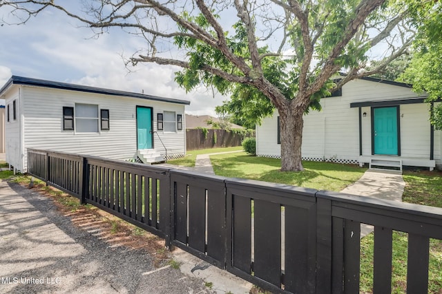 view of front of home featuring entry steps, fence, and a front yard