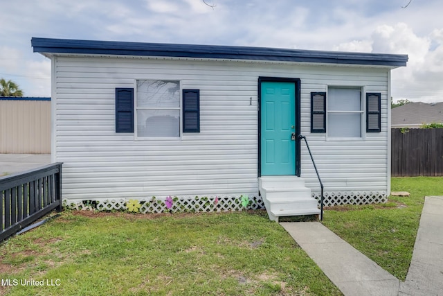 bungalow-style house featuring entry steps, a front lawn, and fence