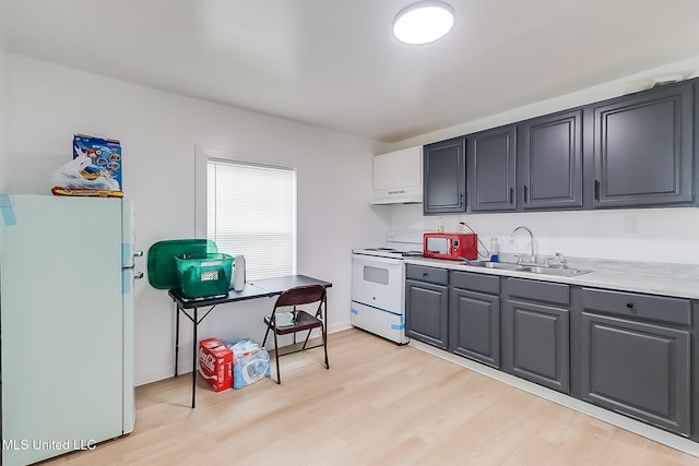 kitchen with white appliances, light countertops, light wood-type flooring, under cabinet range hood, and a sink