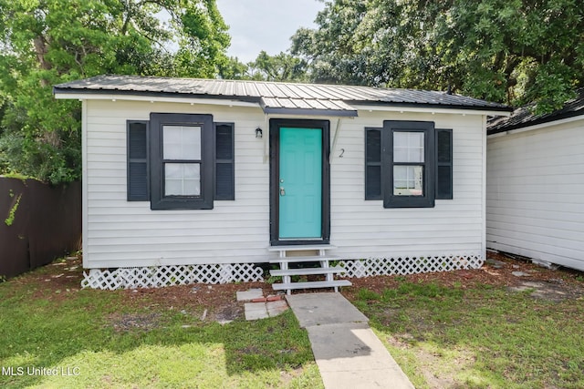 bungalow-style home featuring metal roof, entry steps, and a front yard