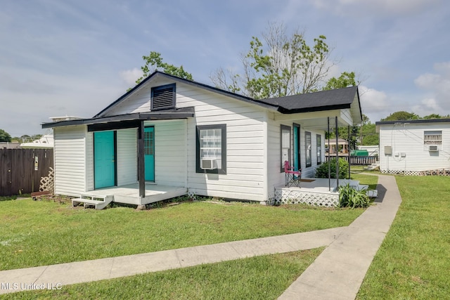 view of front of house with a porch, fence, a front lawn, and cooling unit