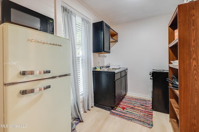 kitchen with freestanding refrigerator, light wood-style flooring, open shelves, and a sink