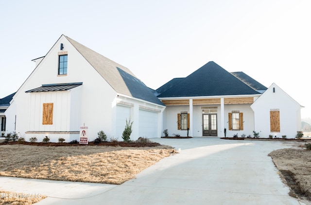 modern inspired farmhouse with french doors, board and batten siding, a standing seam roof, metal roof, and driveway