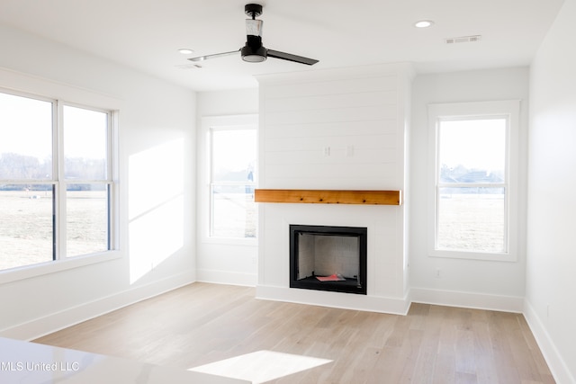 unfurnished living room featuring plenty of natural light, ceiling fan, and light wood-type flooring