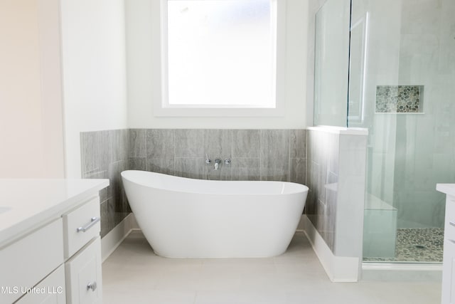 bathroom with tile patterned floors, vanity, tile walls, and plus walk in shower