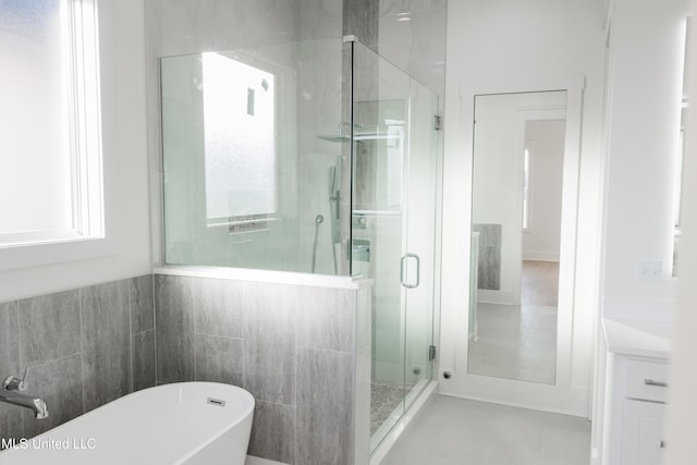 bathroom with separate shower and tub, tile patterned flooring, and tile walls