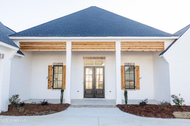 doorway to property with a porch and roof with shingles