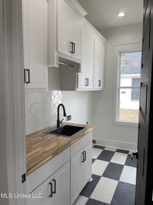 kitchen with white cabinets, decorative backsplash, sink, and wooden counters