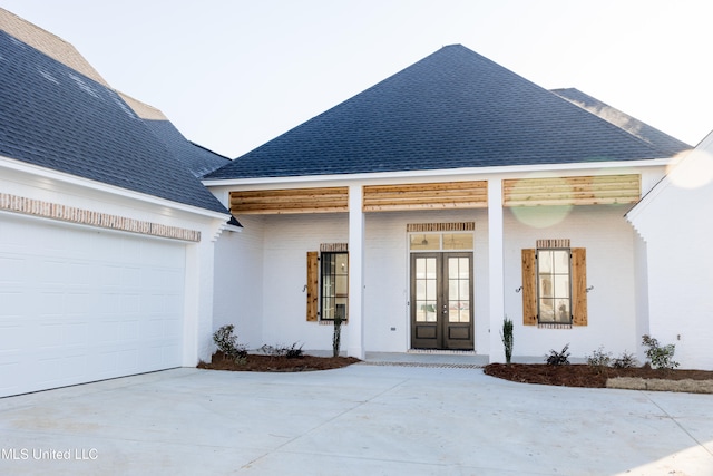 view of front of house featuring concrete driveway, roof with shingles, an attached garage, french doors, and stucco siding