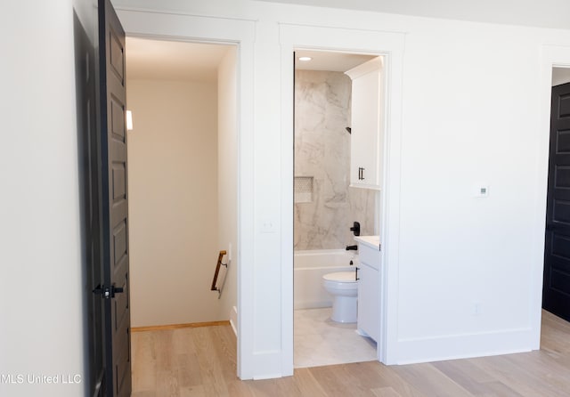 full bathroom with vanity, tiled shower / bath, wood-type flooring, and toilet