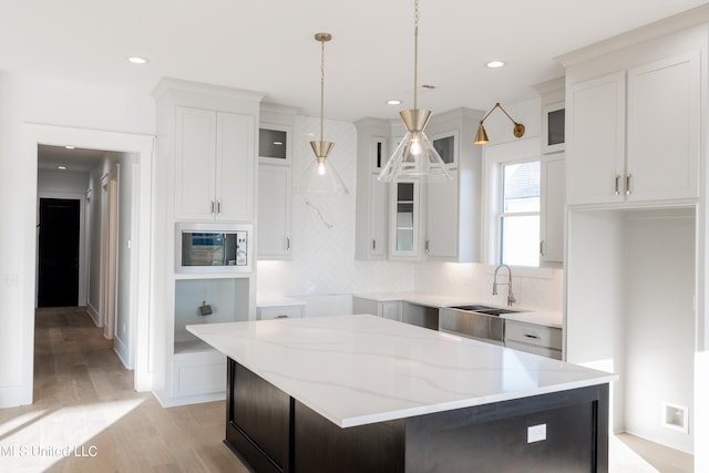 kitchen featuring white cabinets, decorative light fixtures, and a kitchen island