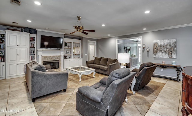 living area with crown molding, a glass covered fireplace, ceiling fan, recessed lighting, and light tile patterned floors