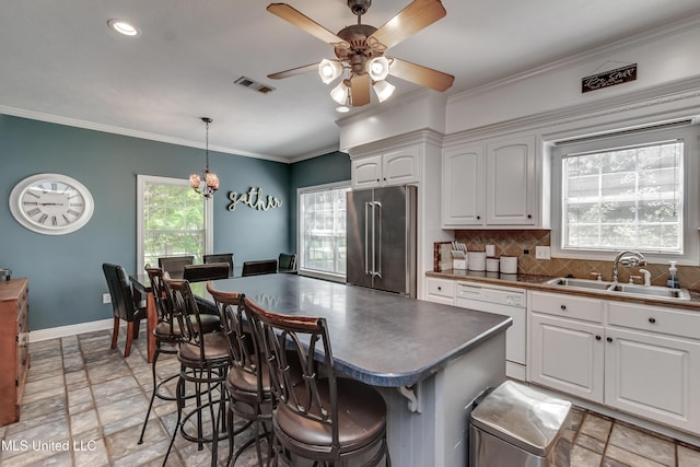 kitchen with dark countertops, a sink, dishwasher, high end refrigerator, and stone tile floors