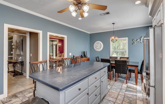 kitchen with dark countertops, ceiling fan with notable chandelier, freestanding refrigerator, white cabinetry, and ornamental molding
