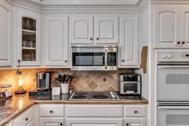 kitchen featuring electric cooktop, glass insert cabinets, white cabinetry, stainless steel microwave, and white double oven