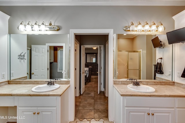 bathroom with two vanities, ornamental molding, a shower stall, and a sink