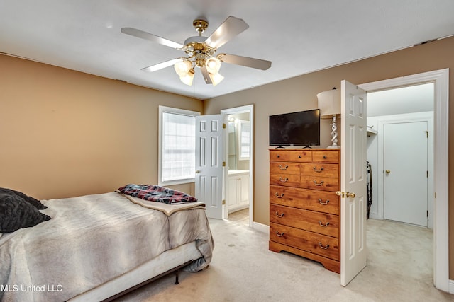 bedroom with a ceiling fan, light carpet, and ensuite bath