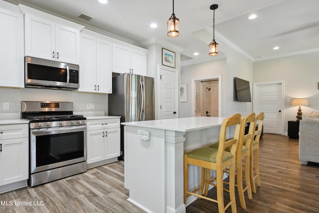 kitchen featuring white cabinetry, stainless steel appliances, light hardwood / wood-style flooring, and hanging light fixtures