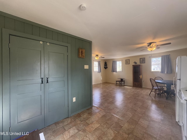 foyer entrance with ceiling fan and wooden walls