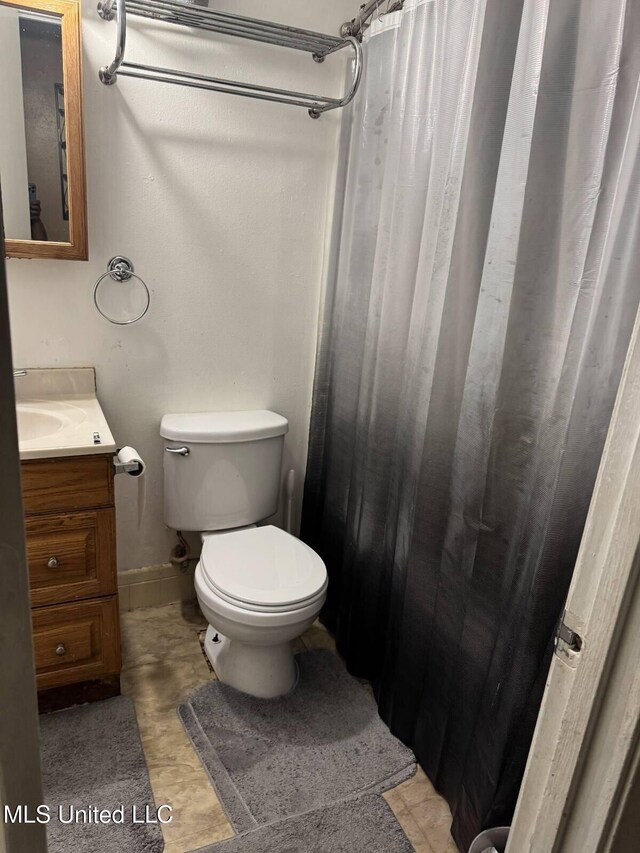 305 John Glenn Ave, Natchez, MS 39120 - bathroom featuring toilet, vanity, baseboards, and a shower with shower curtain