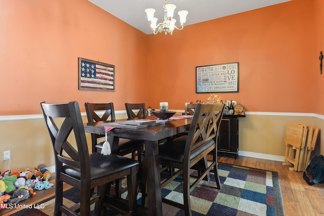 dining space with baseboards, wood finished floors, and a notable chandelier