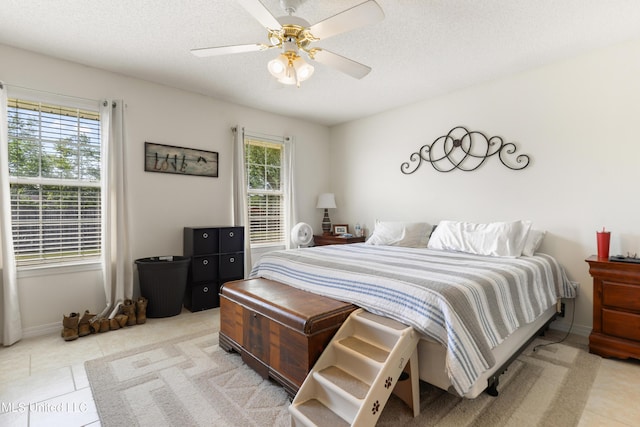 bedroom with light tile patterned floors, baseboards, ceiling fan, and a textured ceiling