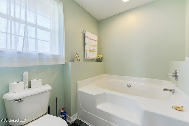 full bath featuring toilet, baseboards, and a bath